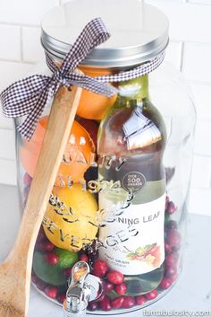 a glass jar filled with fruit and wine next to a wooden spoon