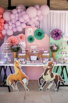 the table is set up with balloons, paper flowers, and horse cutouts on it