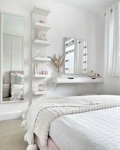 a bedroom with white walls and flooring has a large mirror on the wall above the bed