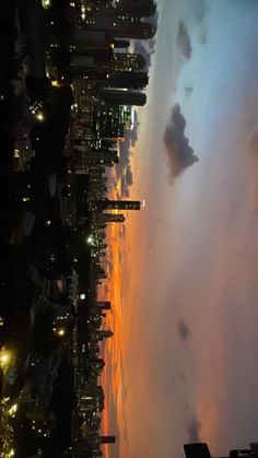 an aerial view of the city at night with clouds and buildings in the foreground