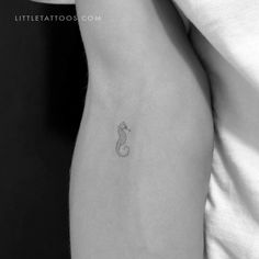 a black and white photo of a woman's arm with a small snake tattoo on it