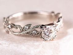 a white gold engagement ring with an oval diamond center surrounded by filigrees