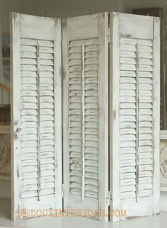 an old white room divider with shutters on the top and bottom panels open