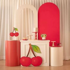 an assortment of furniture with cherries on the top and bottom, in front of a red wall