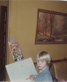 a young boy sitting on a couch holding an open box in front of his face