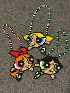 three beaded necklaces with cartoon characters hanging from them on a gray sweater background