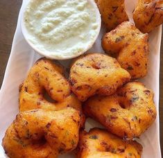 some fried food is on a white plate with a bowl of ranch dressing next to it