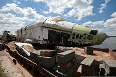 an old airplane sitting on top of a pile of junk next to the ocean with clouds in the background