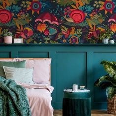 a bedroom with green walls and colorful floral wallpaper, along with a plant in the corner