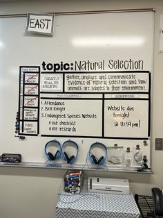 a white board with headphones on it in front of a table and chairs near by