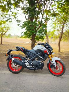 the motorcycle is parked on the side of the road in front of some trees and grass