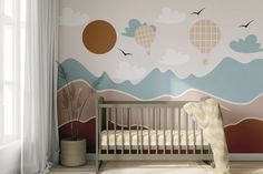 a baby's room with a crib in front of a wall painted with hot air balloons