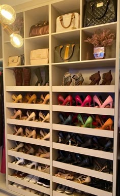 a closet filled with lots of shoes and purses next to a wall mounted light