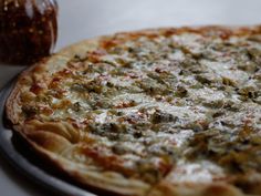 a pizza sitting on top of a metal pan next to a jar of condiments