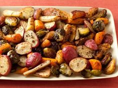 a white plate topped with roasted vegetables on top of a red table