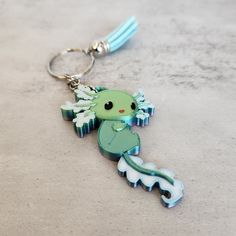 a green and white keychain with an adorable little creature on it's side