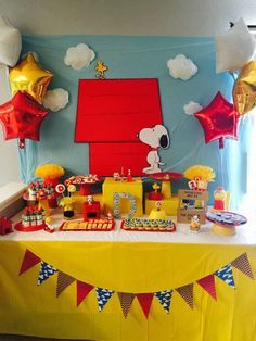 a table topped with balloons and cake next to a red door covered in yellow paper