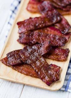 bacon strips on a wooden cutting board with a blue and white checkered table cloth