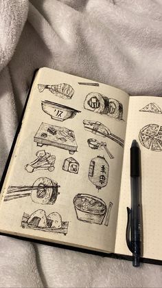 an open notebook with sketches of sushi and chopsticks on it next to a pen