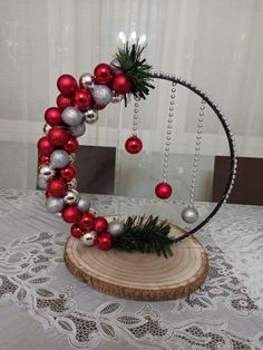 a christmas decoration made out of ornaments on top of a wooden slice with silver and red baubles hanging from it