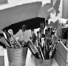 two buckets filled with paint brushes on top of a table