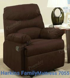 a brown recliner chair sitting on top of a rug next to a table and lamp