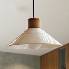 a white light hanging from a ceiling in a room with wooden cabinets and cupboards