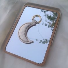 a mirror with a keychain shaped like a crescent moon hanging from it's side