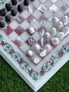 a marble chess board with black and white pieces on the grass in front of it