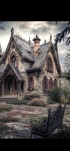 an old abandoned house with a bench in the foreground and cloudy sky above it