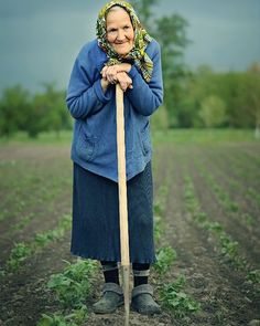 a woman standing in a field holding a stick