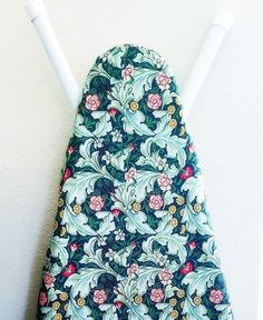 an ironing board cover with flowers on it and two white poles sticking out of the back