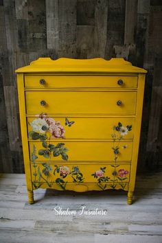 a yellow dresser with flowers painted on it