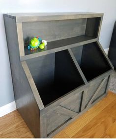 a wooden shelf with two bins on top of it and toys in the bottom