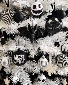 a white christmas tree with black and white ornaments on it's branches is decorated in the style of jack skellings