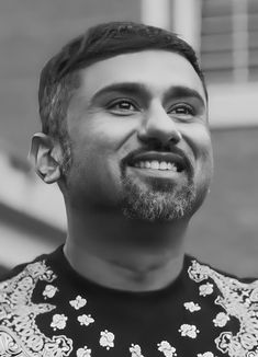 a black and white photo of a man with a goatee smiling at the camera