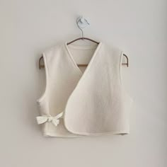 a white sweater vest hanging on a wooden hanger