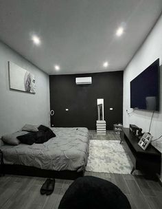 a black and white photo of a bedroom with a tv on the wall, bed in the foreground