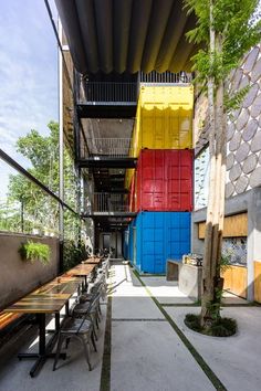 an outdoor dining area with tables and chairs in front of multicolored doors on the building