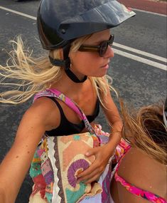 a woman wearing a helmet and carrying a bag on her back while walking down the street