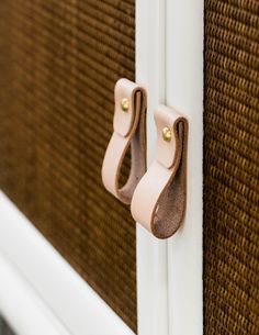 a close up of a door handle on a white frame with brown and tan trim