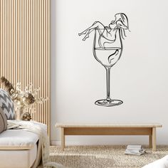 a living room with a couch, coffee table and wall decal that has a drawing of a woman in a wine glass on it