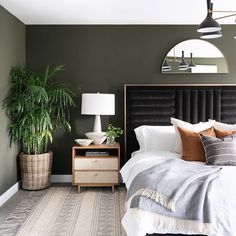 a bedroom with a bed, nightstand and potted plant on the side table in front of it