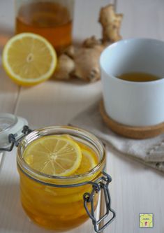 a glass jar filled with liquid next to sliced lemons and ginger florets