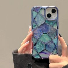 a woman holding up her phone case with blue and green mosaic tiles on the back