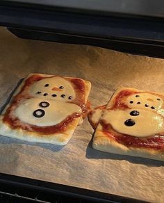 two pizzas that have been made to look like ghost faces on them, sitting in an oven