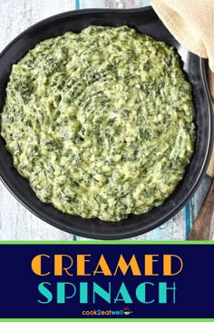 a skillet filled with creamed spinach on top of a wooden table