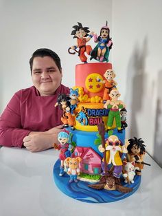 a man sitting in front of a dragon ball cake with figurines on it