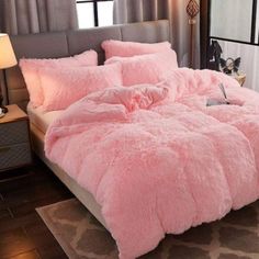 a bed with pink fluffy comforter and pillows