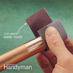 a hand holding a sanding tool with an emery cloth on it's end